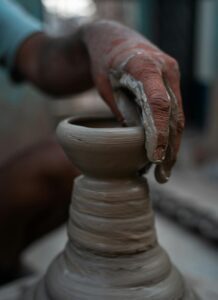person molding a clay pot