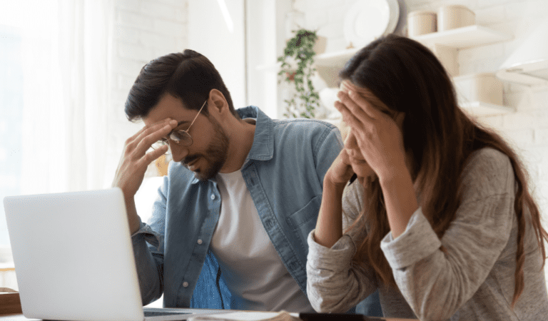 Couple looking worried while checking their laptop