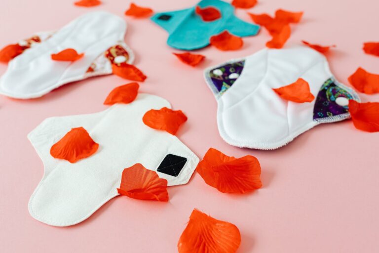 reusable cotton pads on pink surface with flower petals